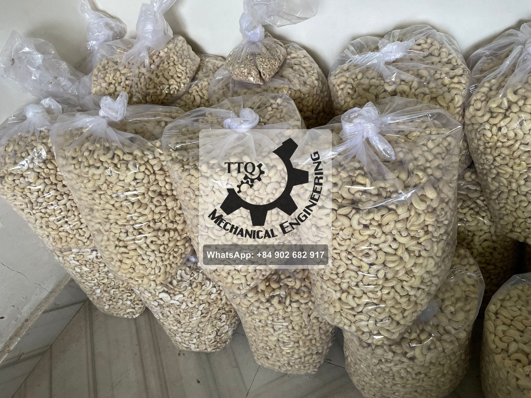 Bags of white cashew kernels stacked in a store, sorted by grade