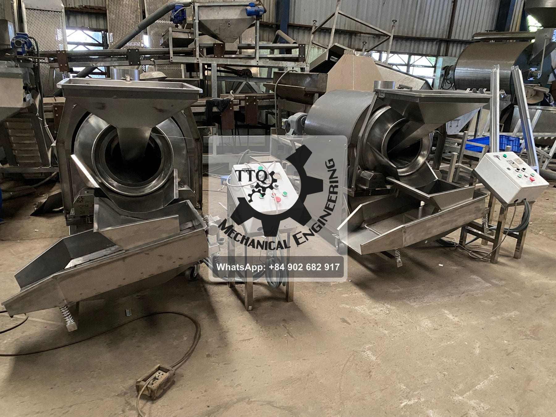 Two TTQ drum roasters side by side in the workshop, each with its own control pedestal